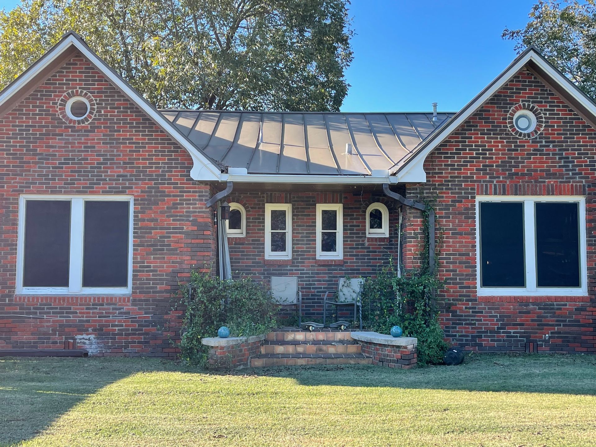 A red brick house with white windows and a screened in porch.
