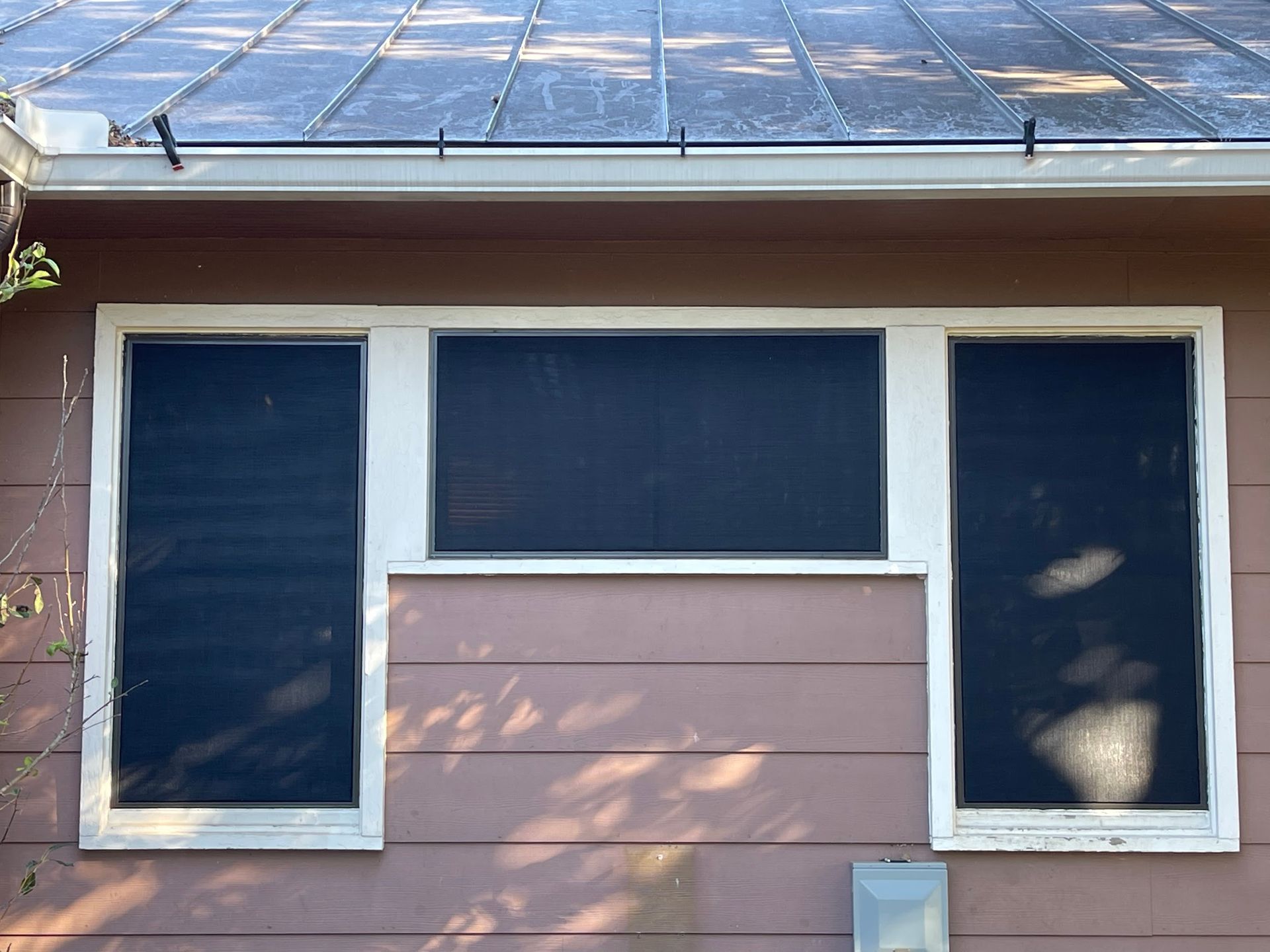 A pink house with three windows and a gutter