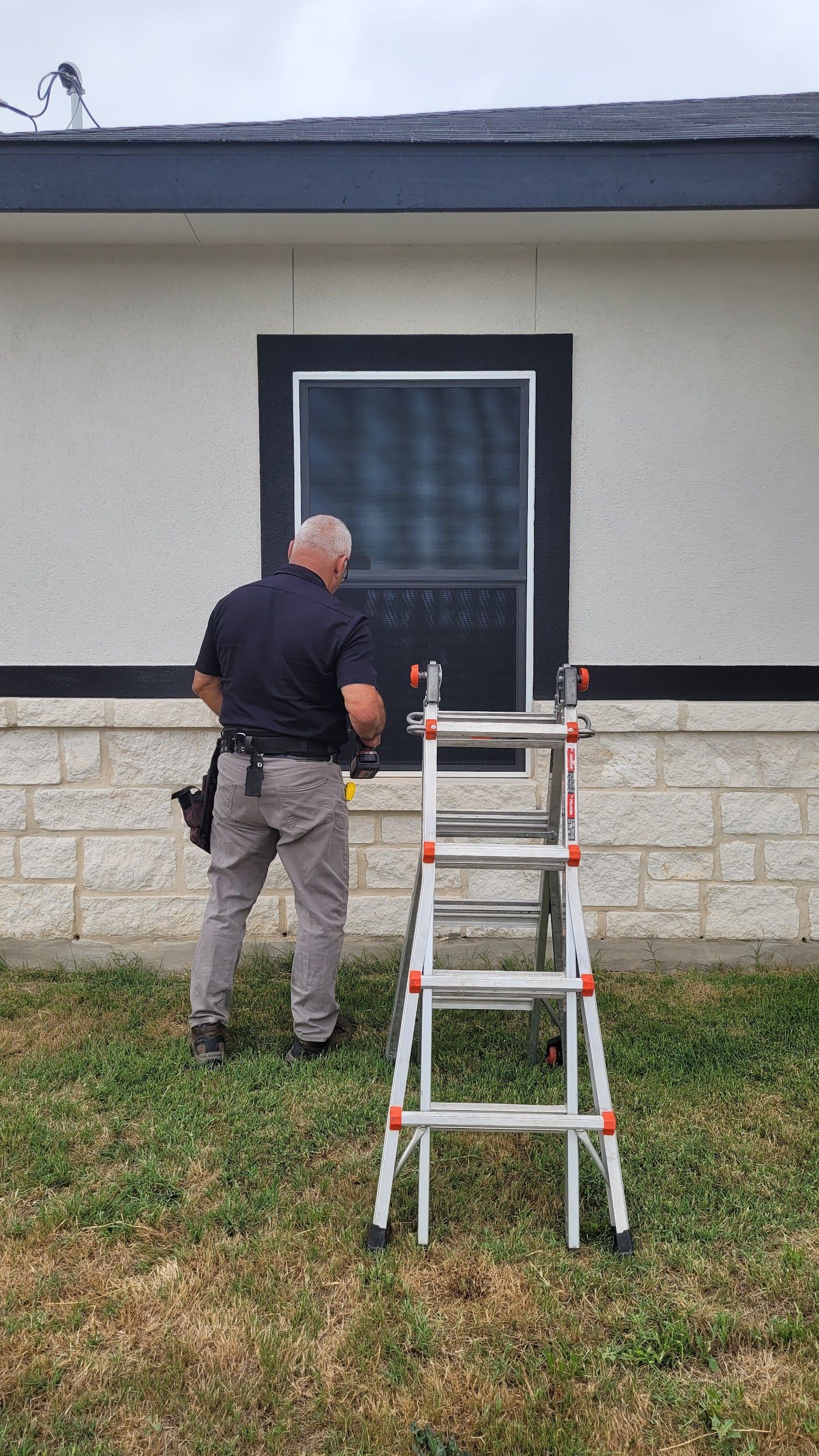 A man is standing next to a ladder in front of a house.