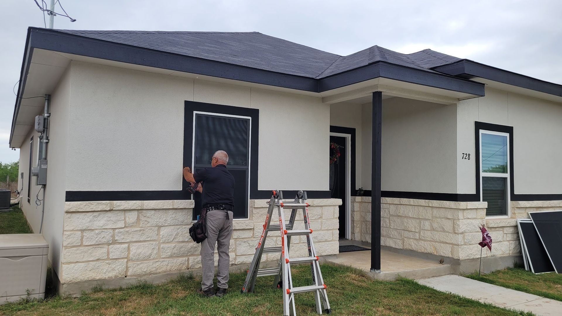 A man is installing a window on the side of a house.