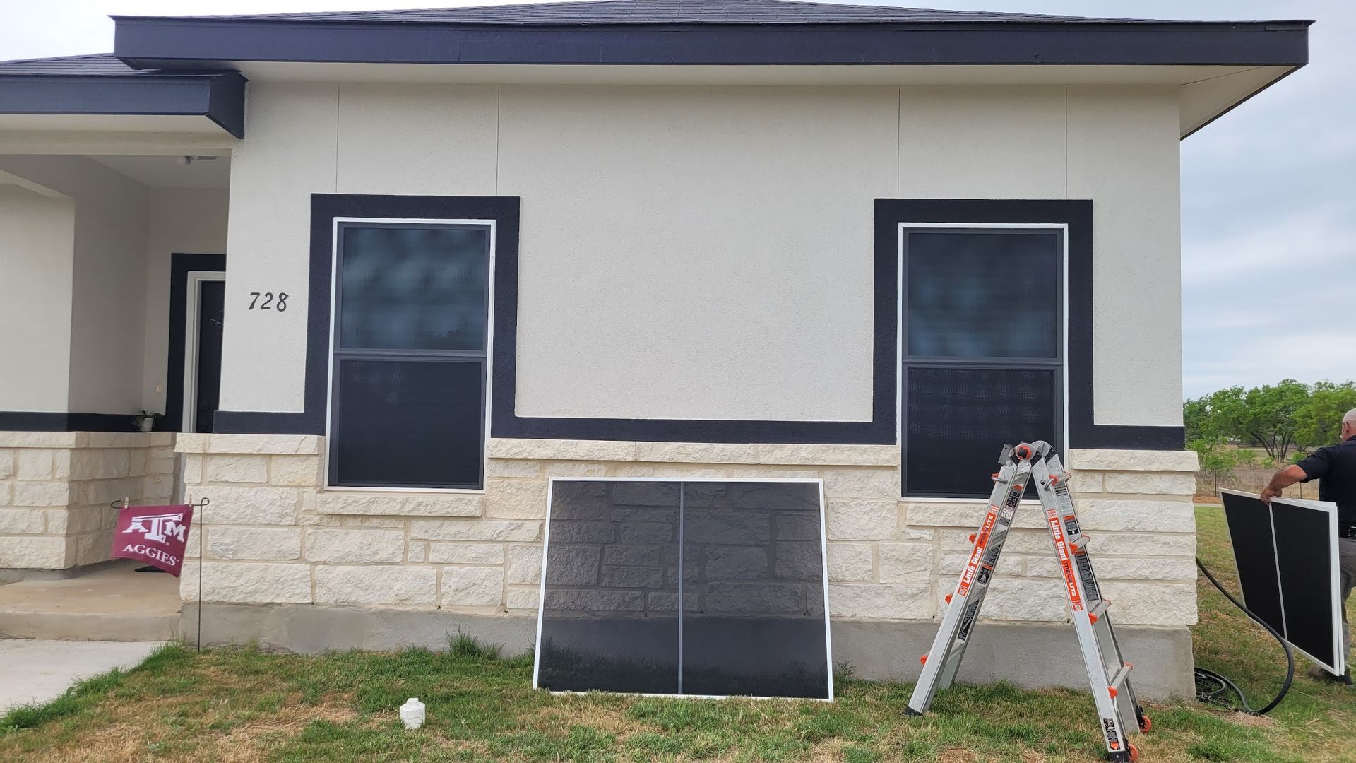 A man is standing in front of a house with a ladder in front of it.