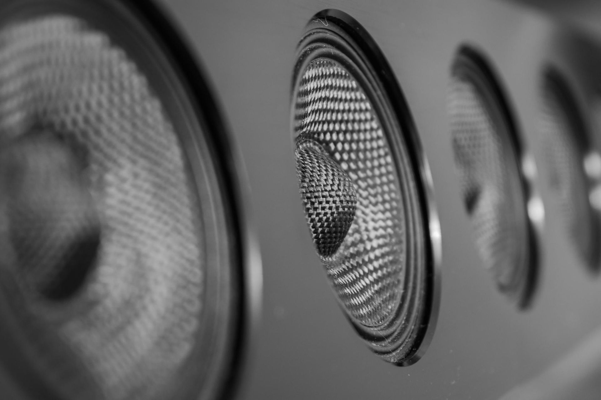 Close-up of three round speaker grilles in grayscale on a wall