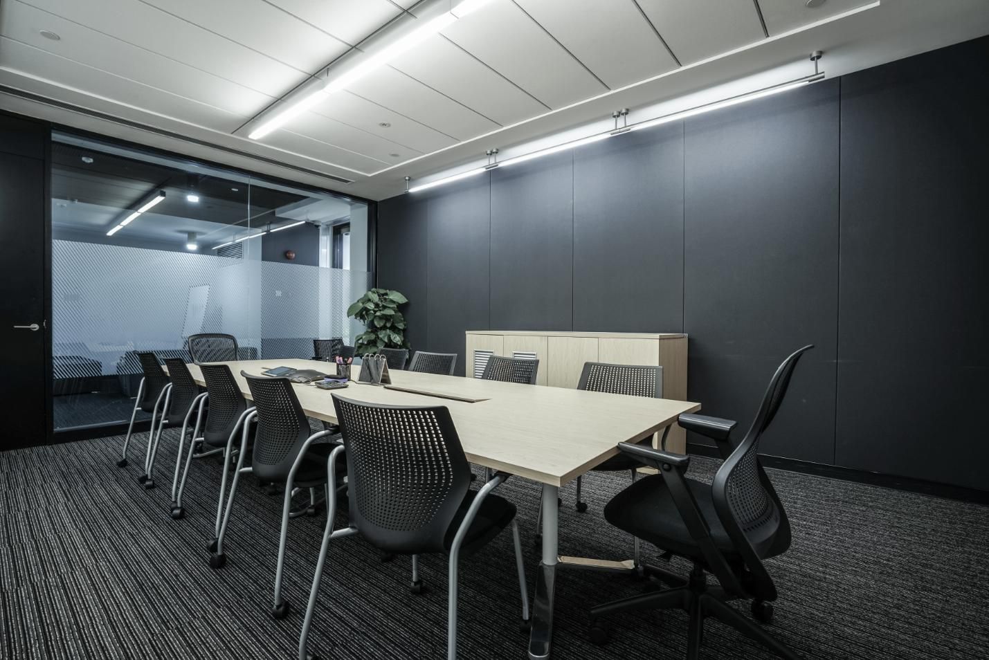 Modern conference room with a long table, black chairs, and glass walls in a sleek gray interior