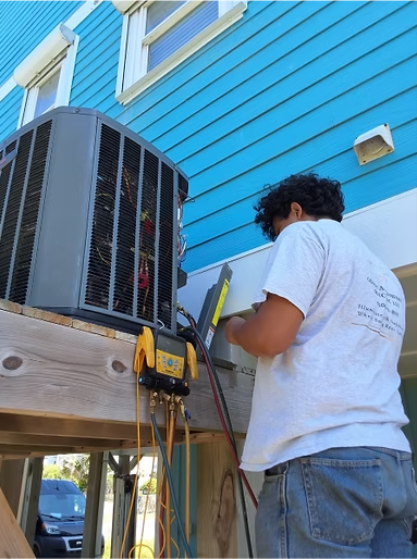 A man in a white shirt is working on an air conditioner