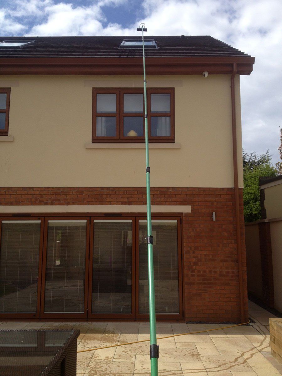 A green cleaning pole in front of a modern house