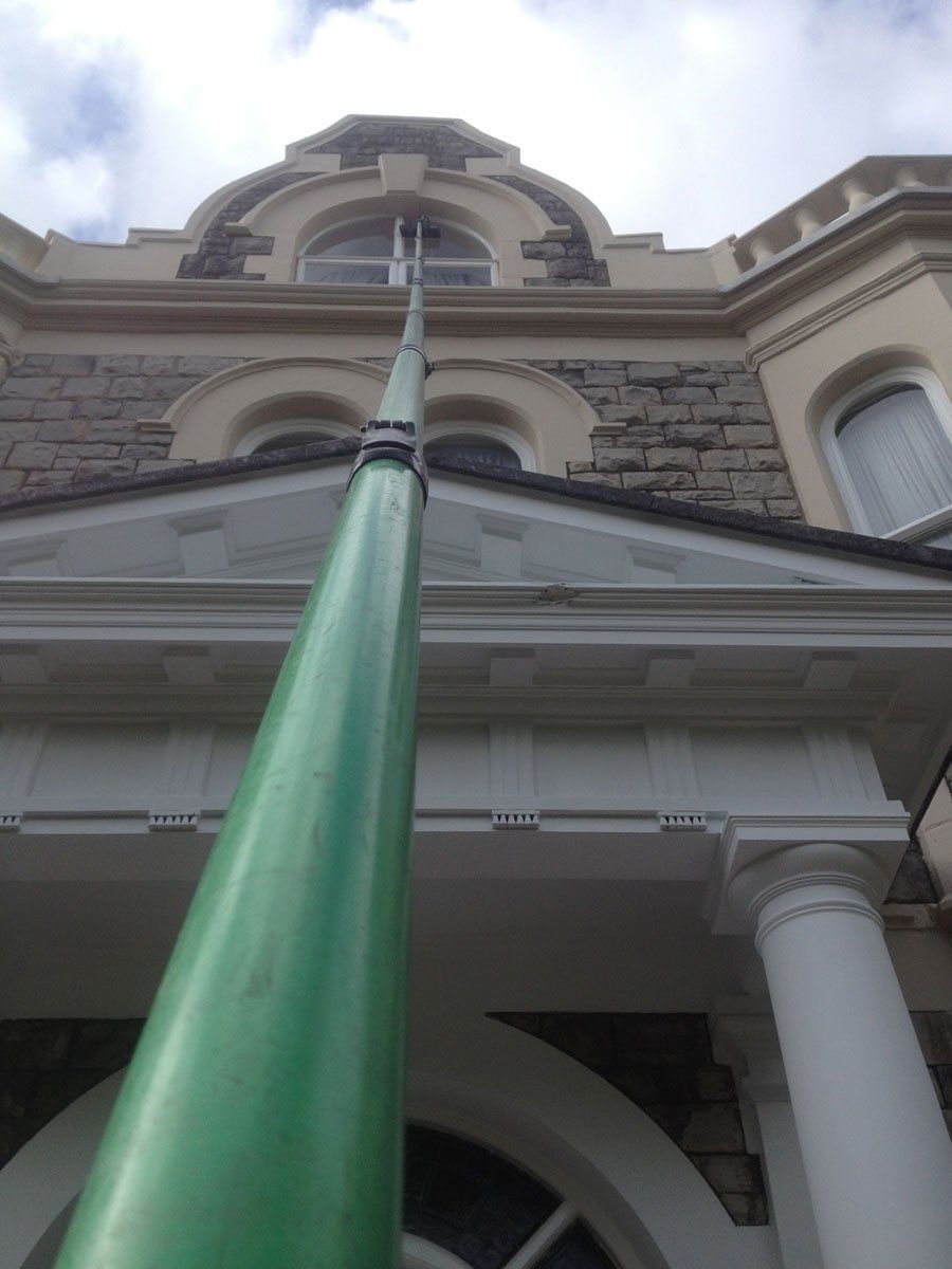A green cleaning pole in front of a traditional house