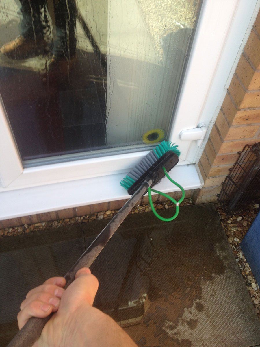 A green brush cleaning white uPVC windows