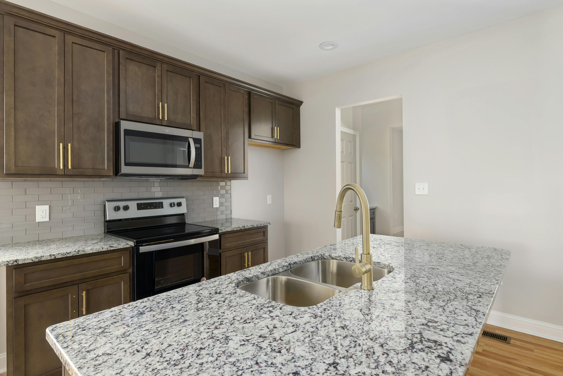 Kitchen with brown cabinets, granite countertops, stainless steel appliances, and a gold faucet.
