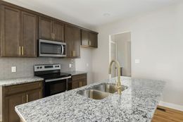 Kitchen with brown cabinets, granite countertops, stainless steel appliances, and a gold faucet.