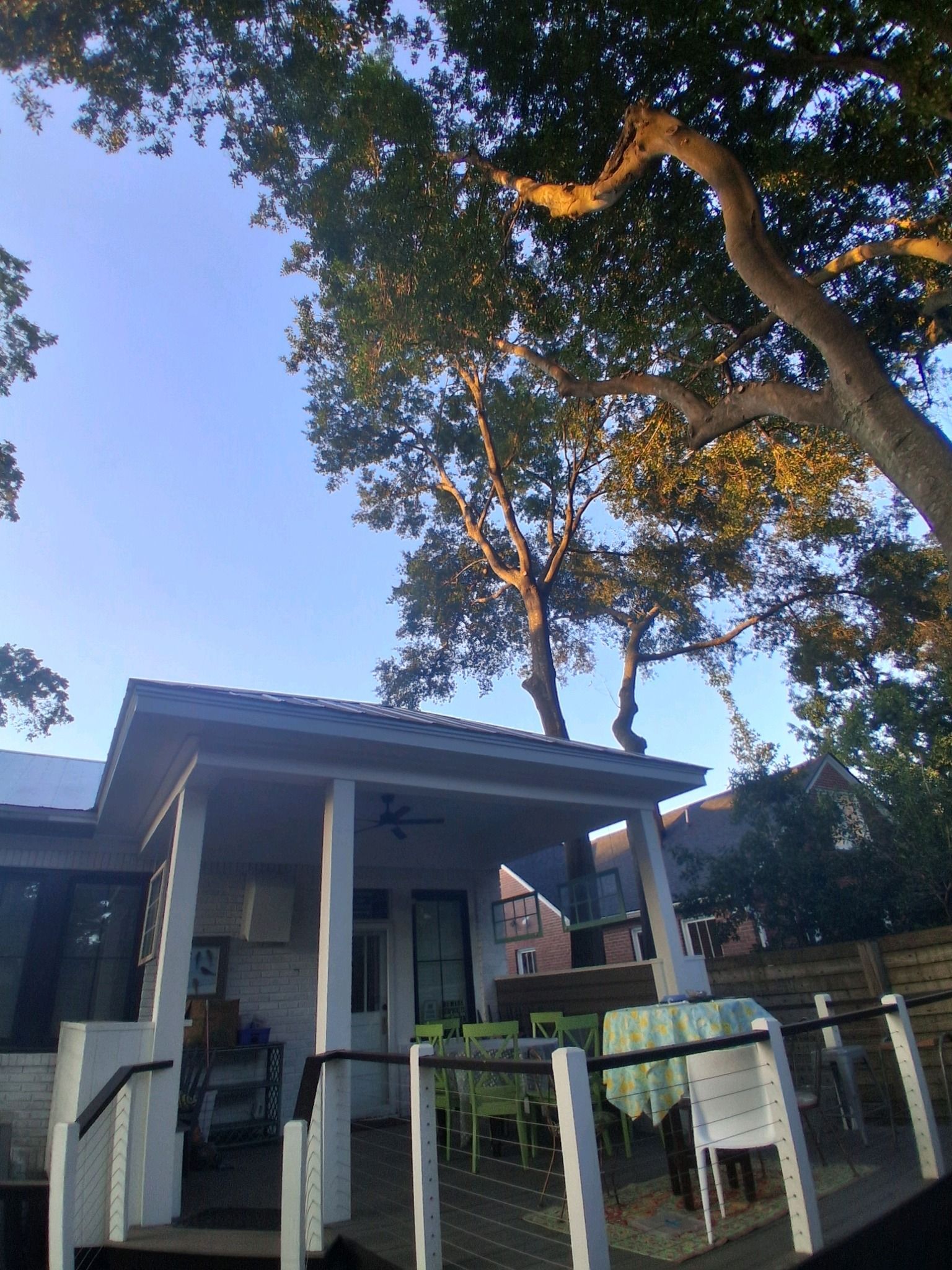A house with a porch under trees. The sky is blue.