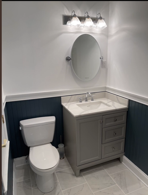 A bathroom with a toilet , sink and mirror.