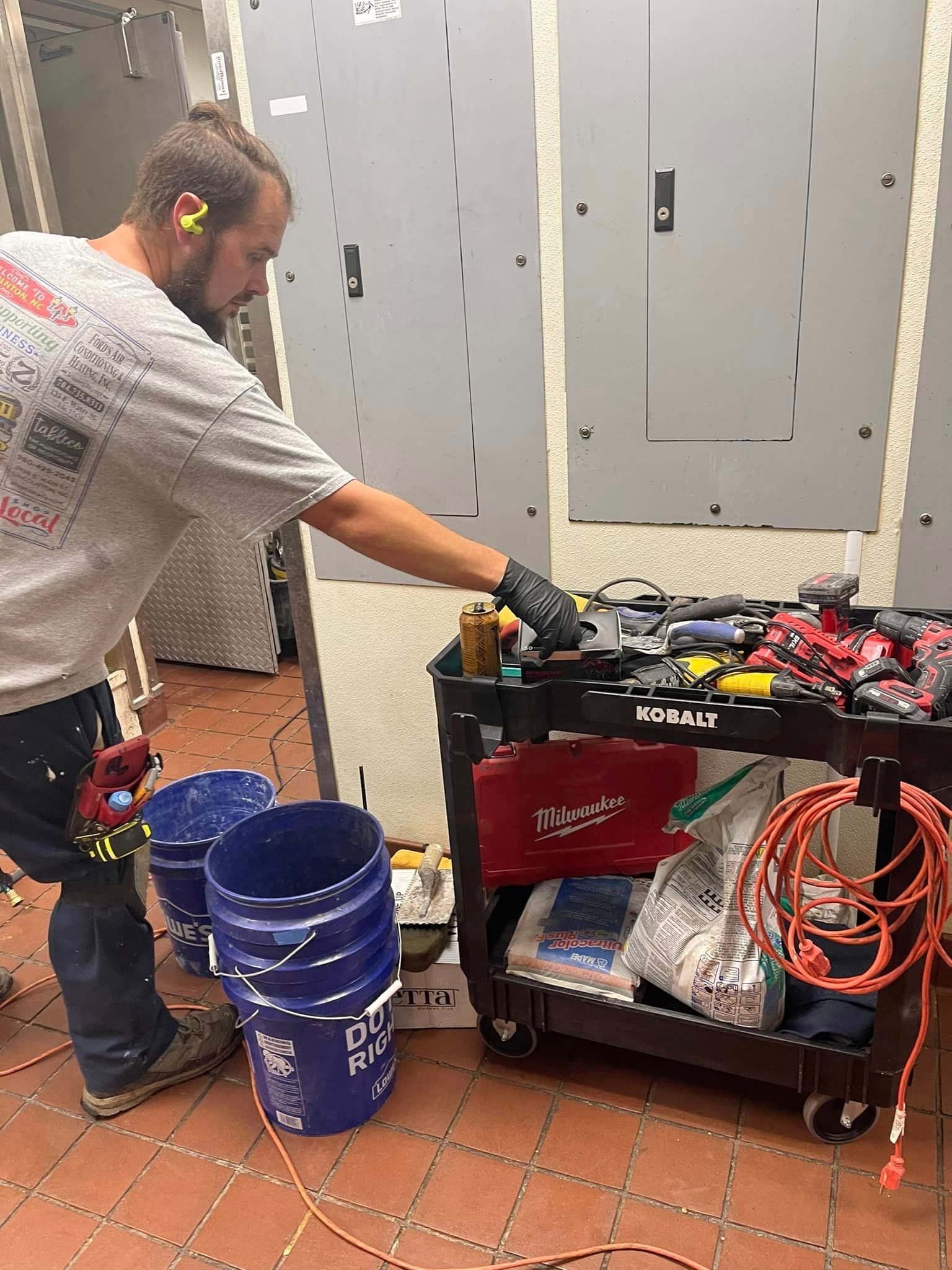A man is standing in front of a cart filled with tools.