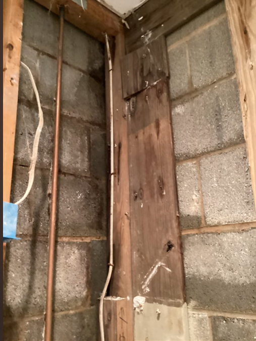 A corner of a brick wall with wooden beams and pipes