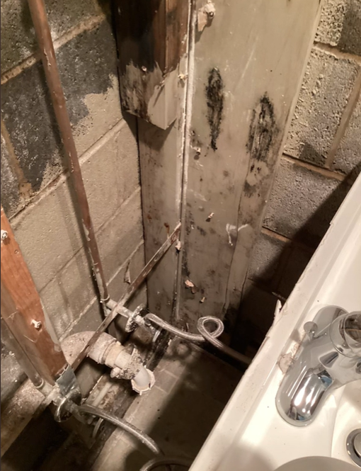 A bathroom with a sink , faucet and pipes.