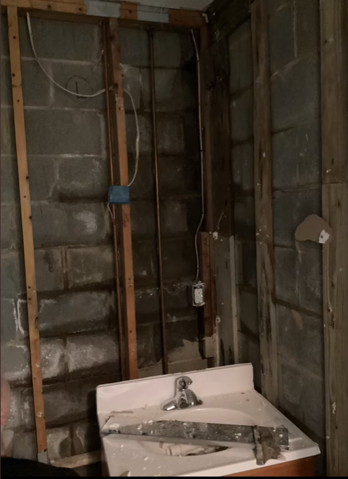 A bathroom with a sink and a brick wall