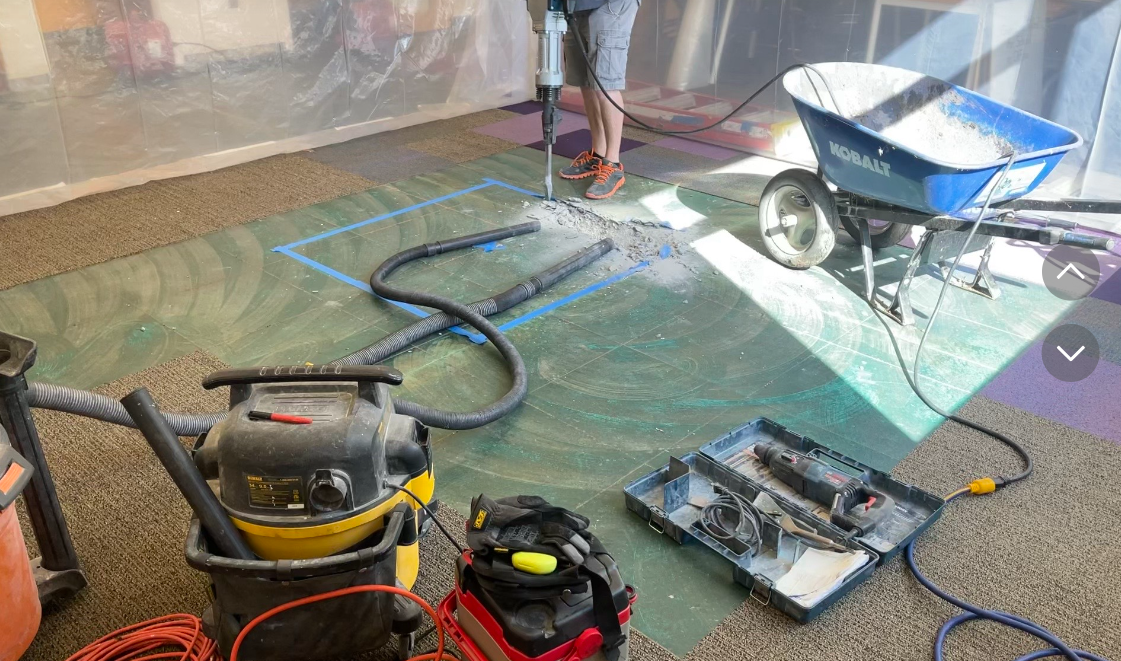 A man is using a hammer to drill a hole in the floor.