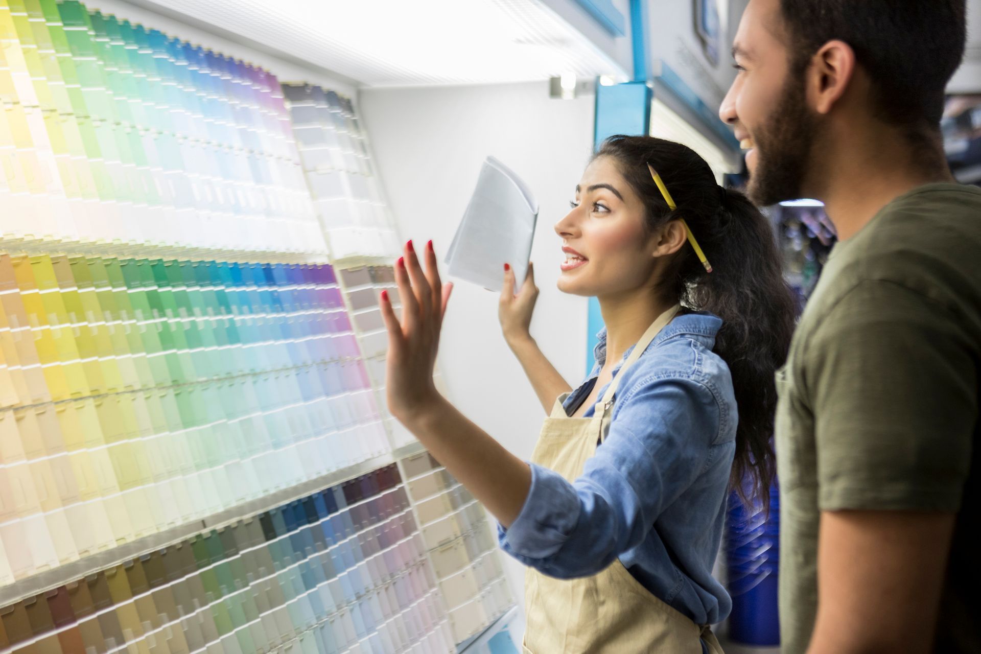 A man and a woman are looking at paint samples in a paint store.