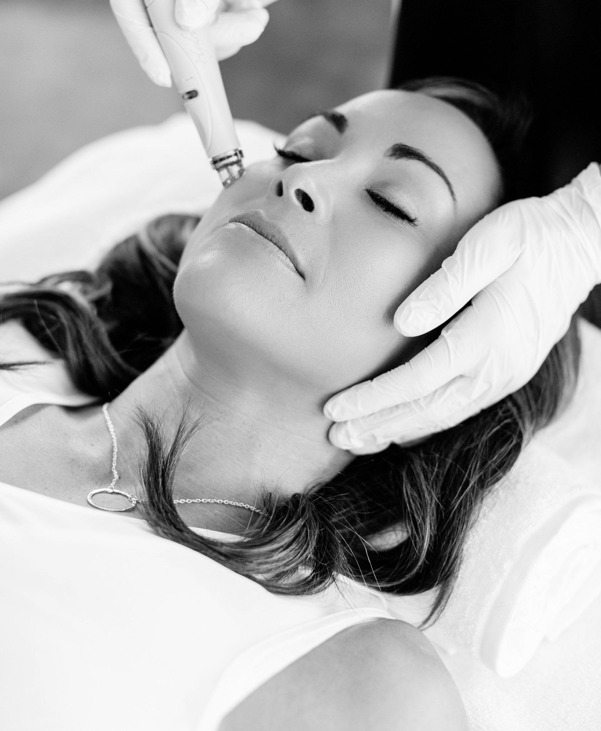 A woman is getting a facial treatment in a black and white photo.