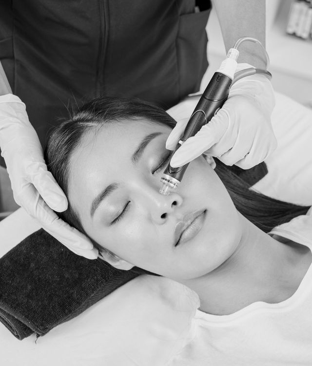 A woman is getting a facial treatment in a black and white photo.