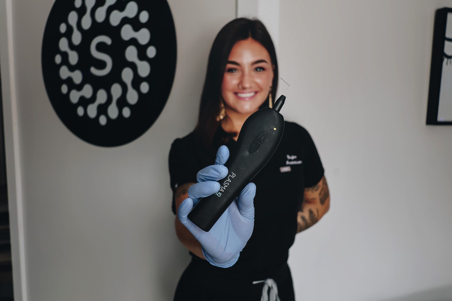 A woman in a black shirt and blue gloves is holding a black object.