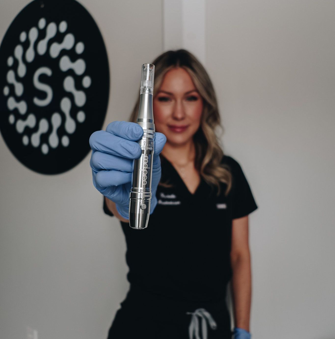 A woman in scrubs is holding a machine in her hand.