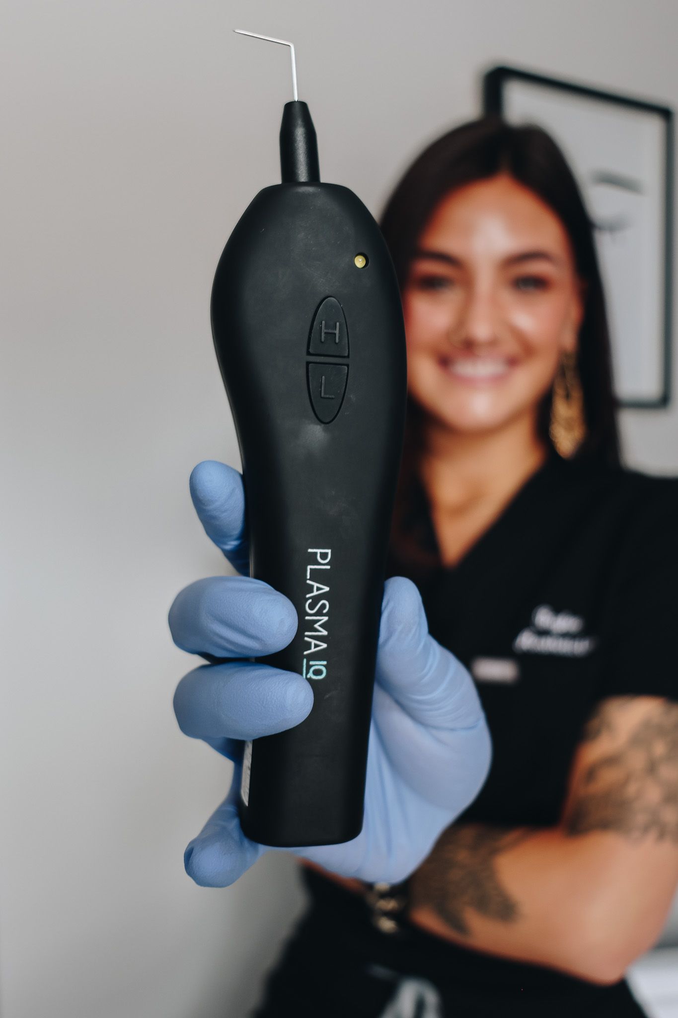 A woman in blue gloves is holding a black device that says ' plasma ' on it