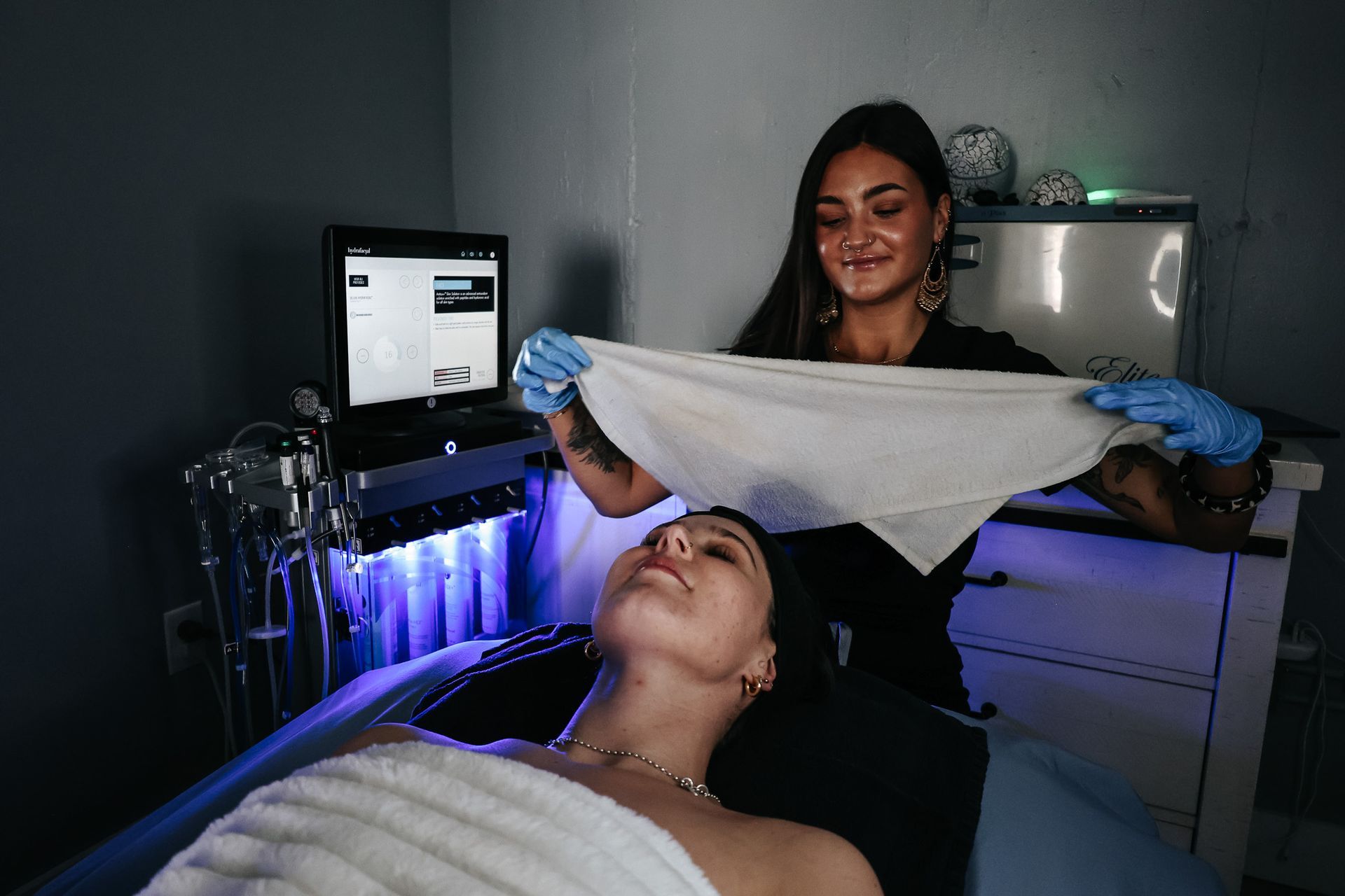 A woman is holding a towel over a woman 's face.