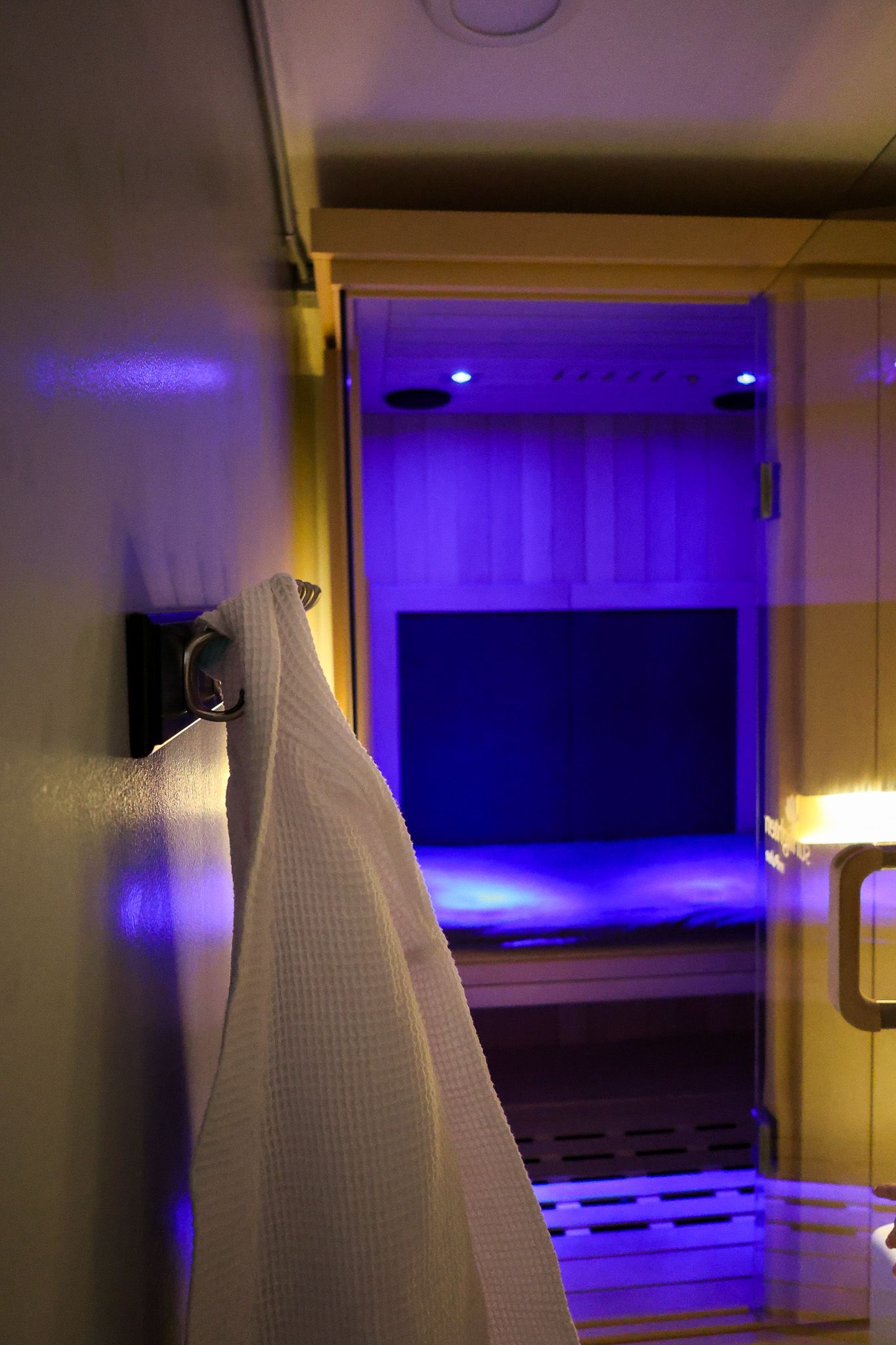 A towel is hanging on a hook in a bathroom next to a sauna.