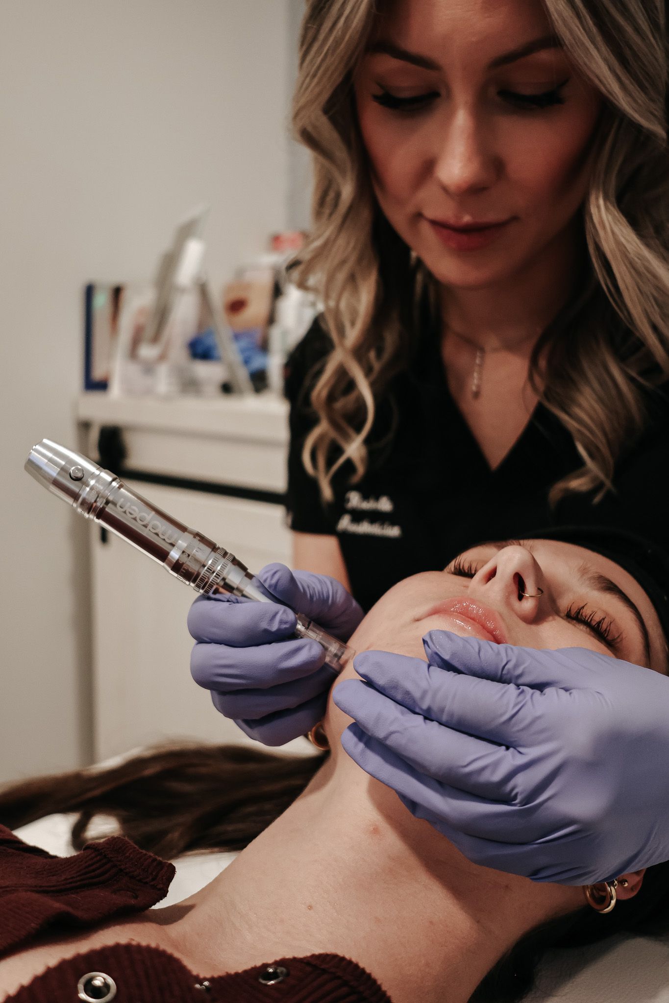 A woman is using a machine on a woman 's face in a beauty salon.