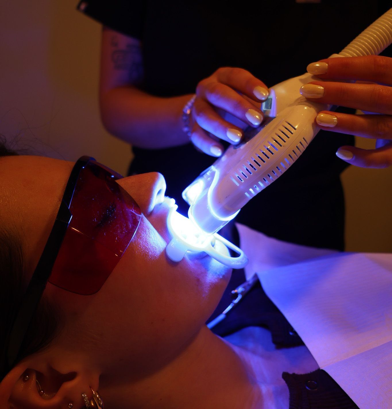 A woman is getting her teeth whitened by a dentist