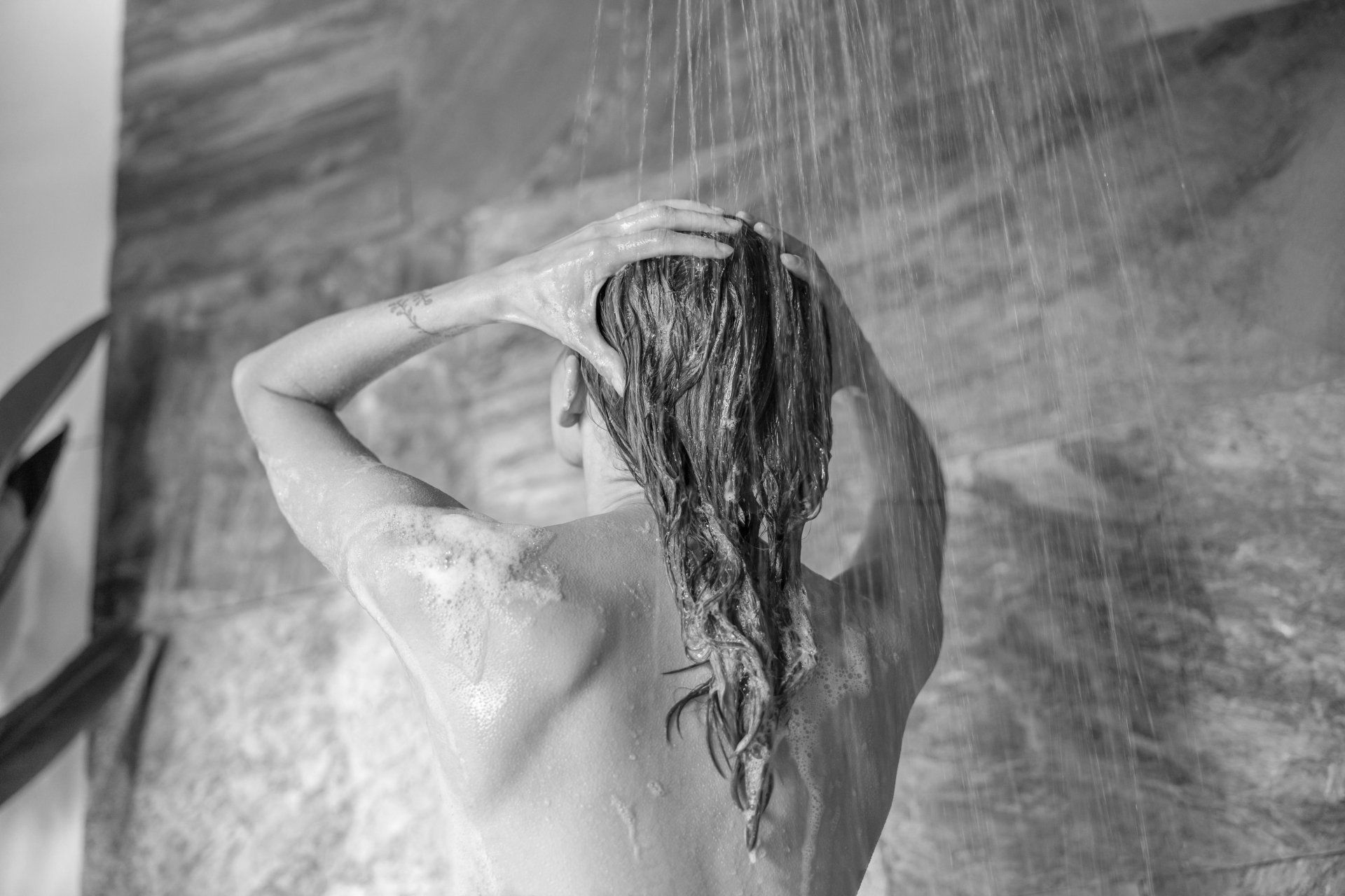 A woman is taking a shower in a black and white photo.