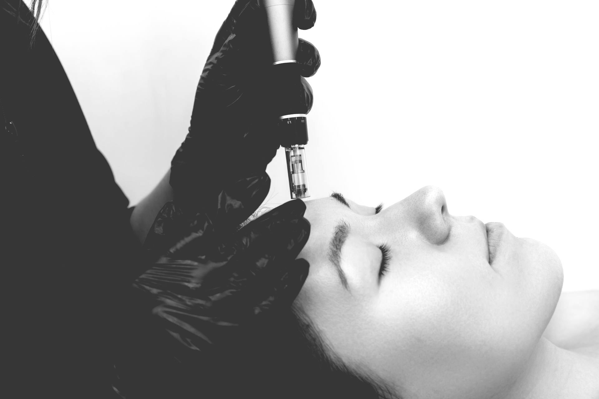 A woman is getting a facial treatment in a black and white photo.