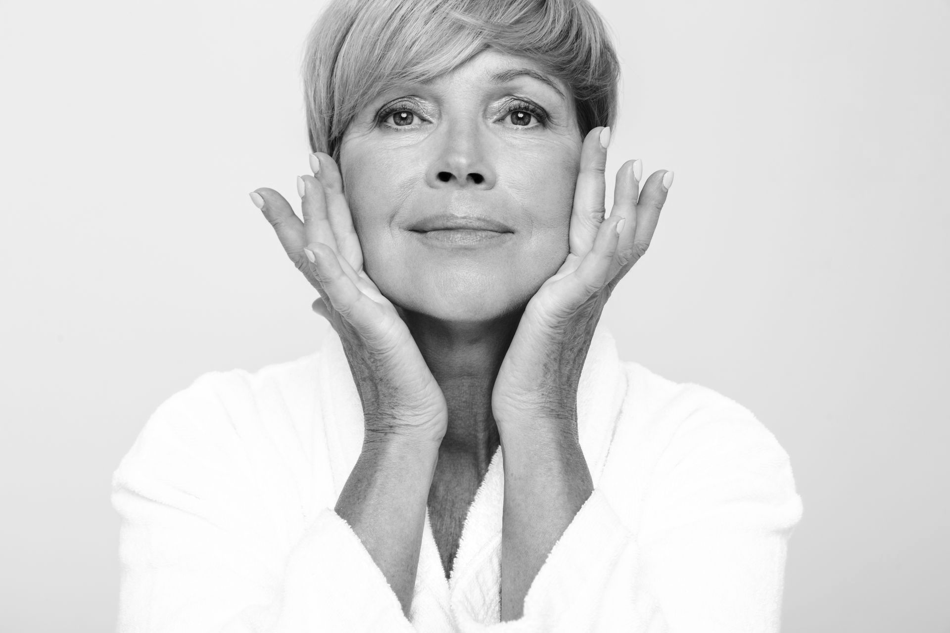 A woman is touching her face with her hand in a black and white photo.