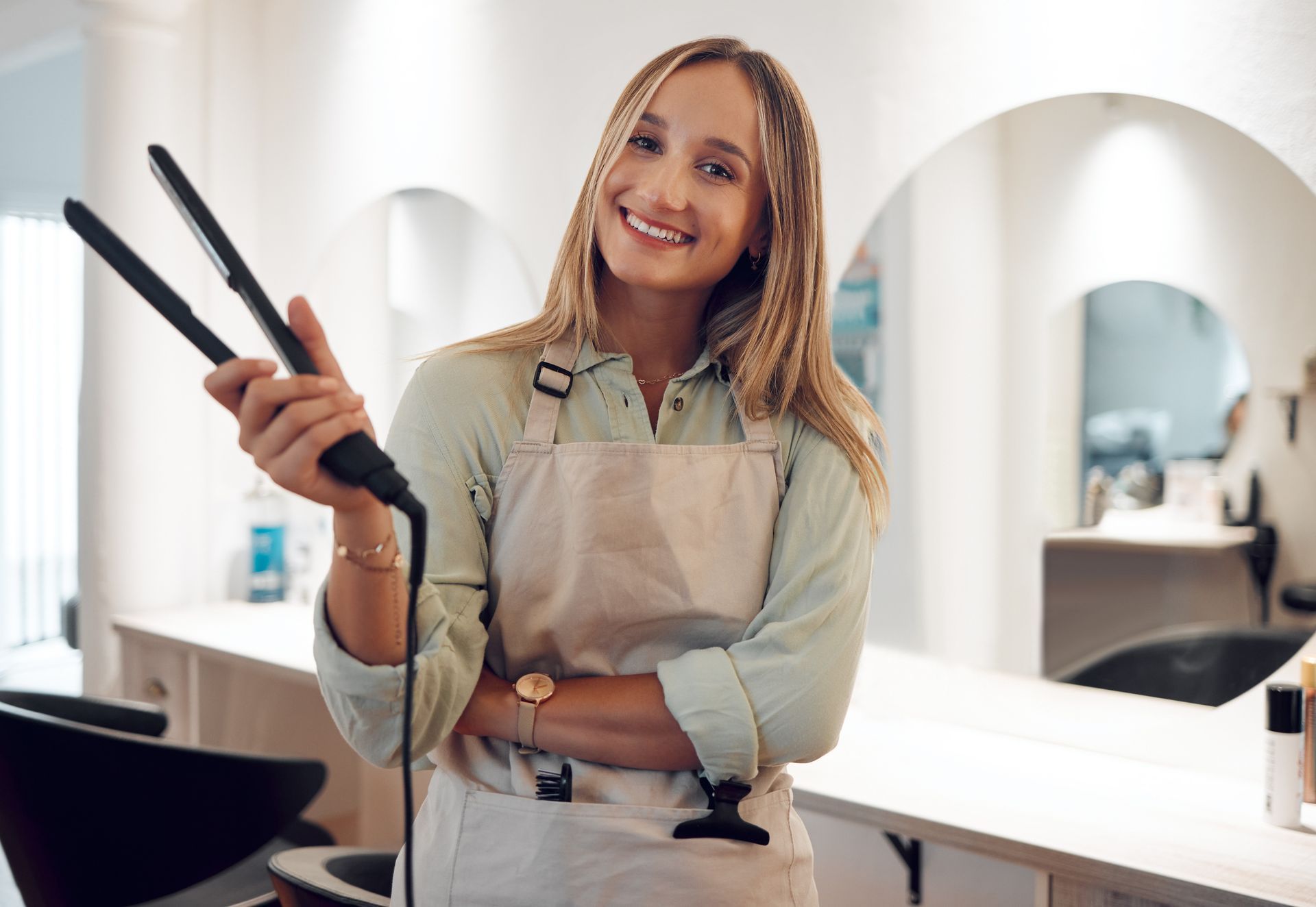 A woman is holding a hair straightener in a hair salon.