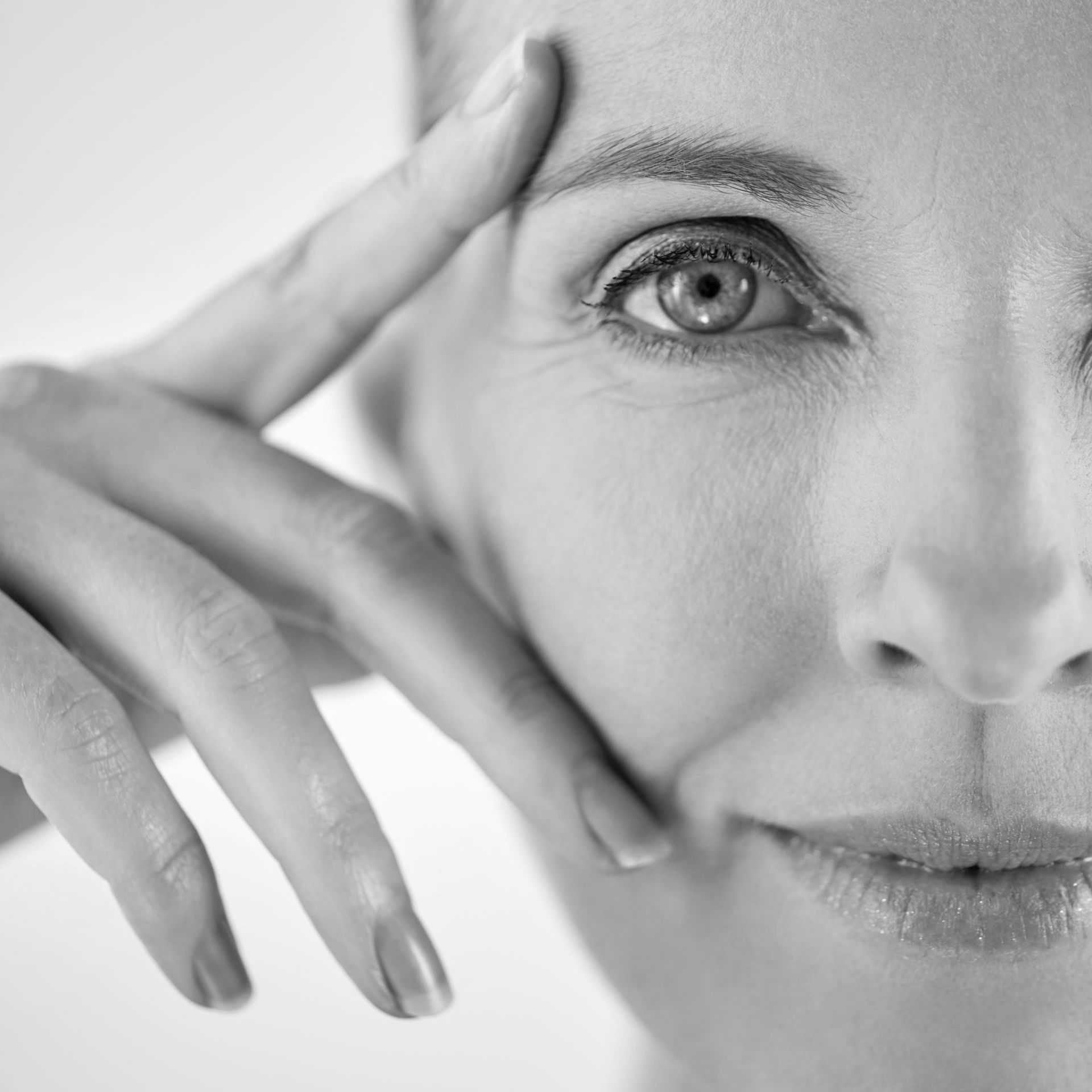 A woman is touching her face with her hand in a black and white photo.