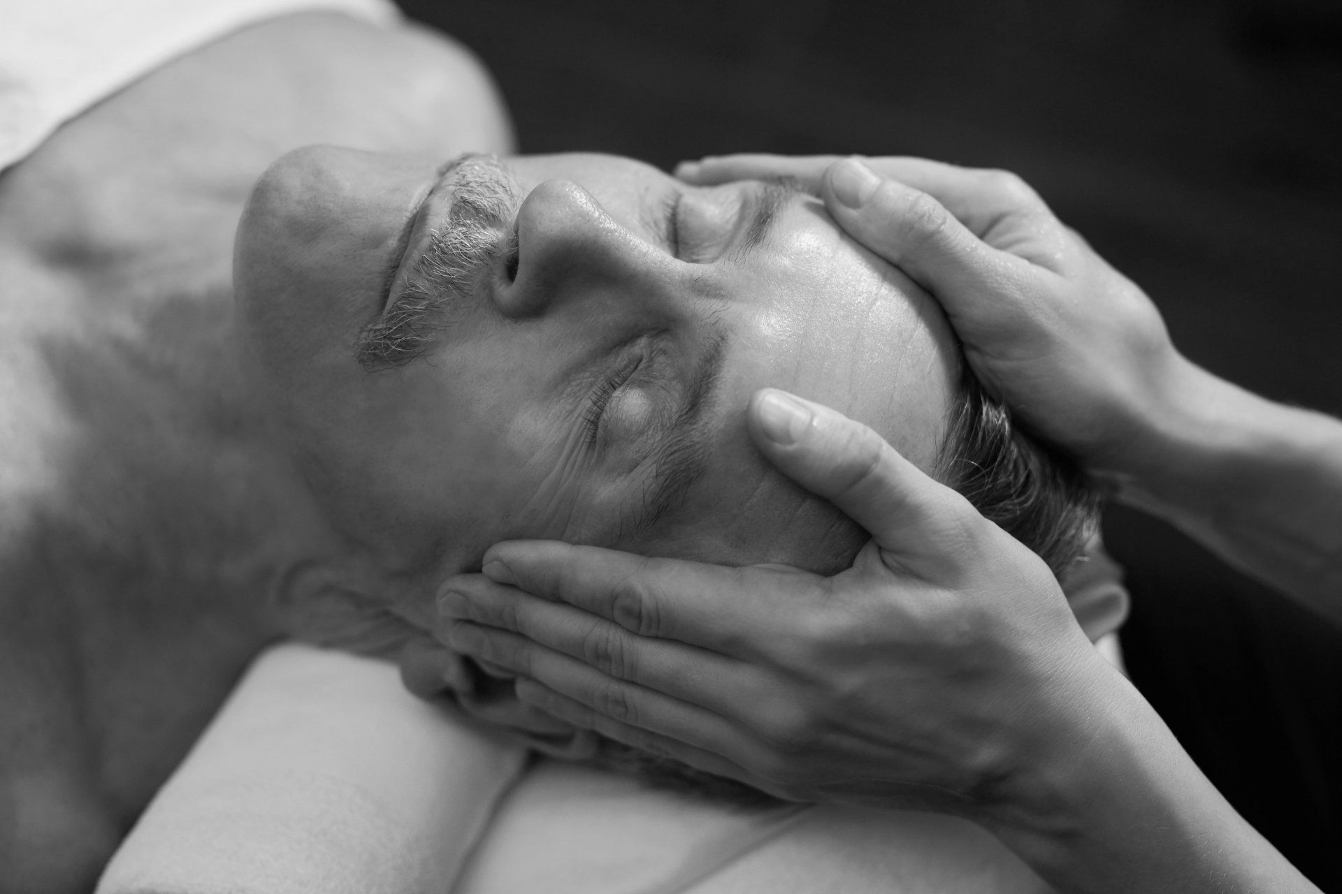 A man is getting a head massage in a black and white photo.