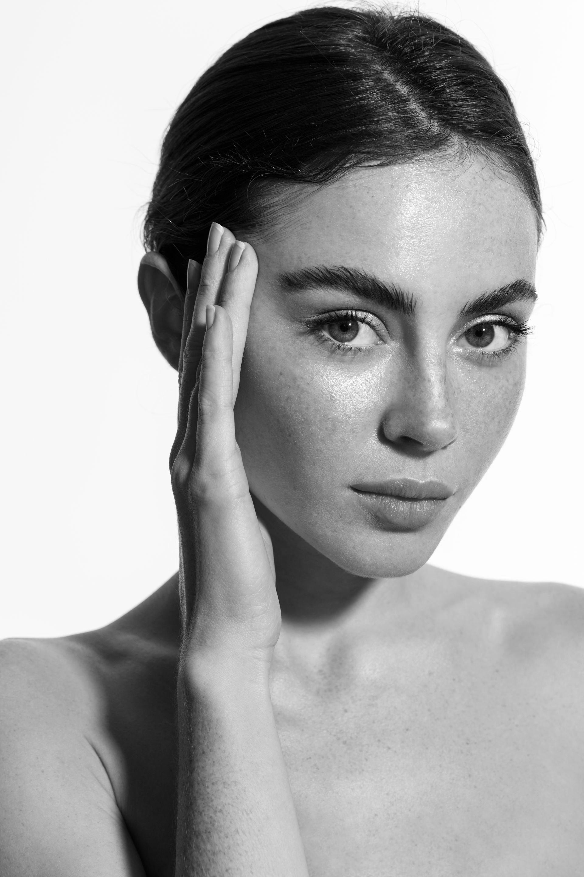 A woman is touching her face with her hand in a black and white photo.