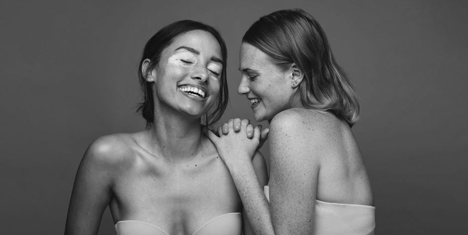 Two women are standing next to each other and smiling in a black and white photo.