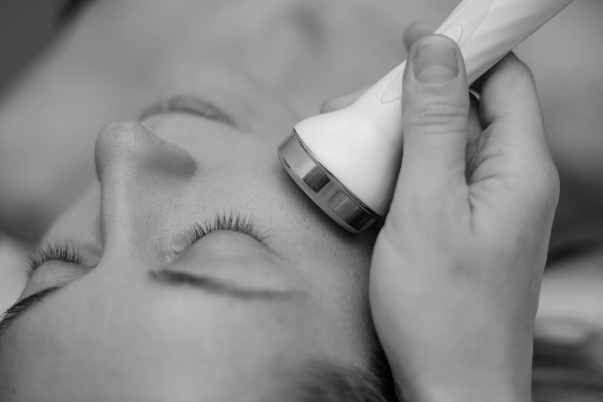 A woman is getting an ultrasound treatment on her face.