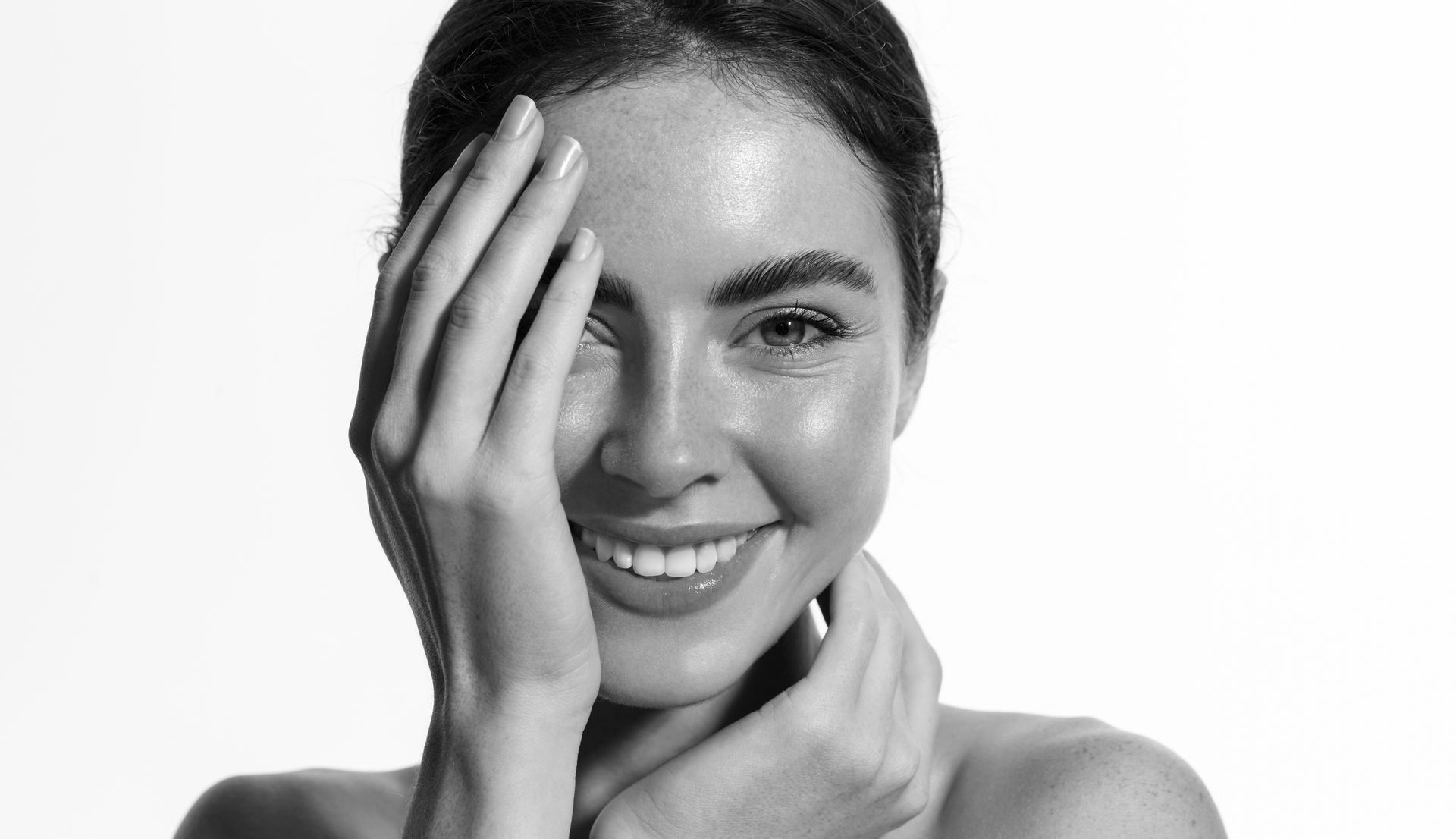 A woman is smiling and covering her face with her hand.