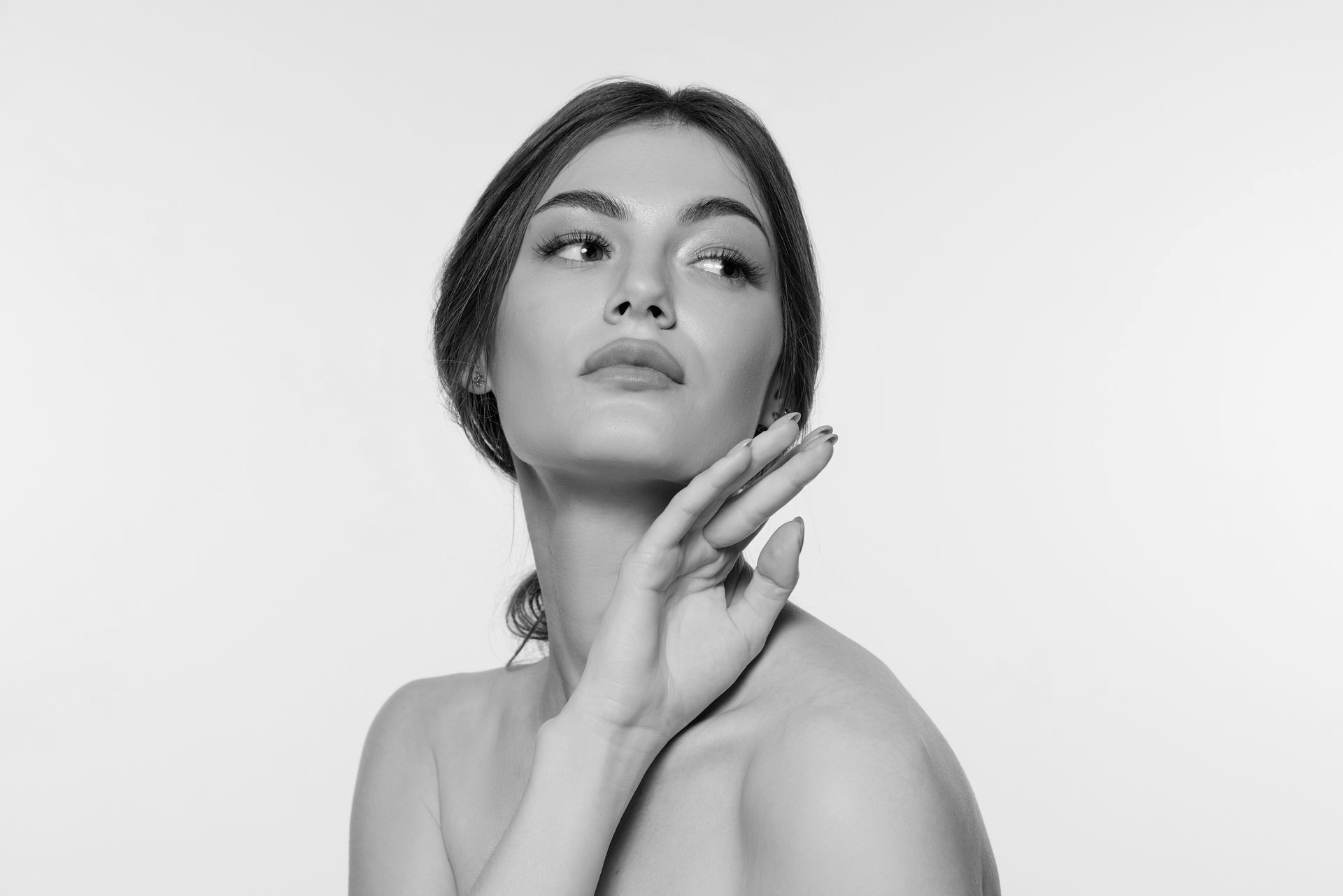 A woman is touching her face in a black and white photo.