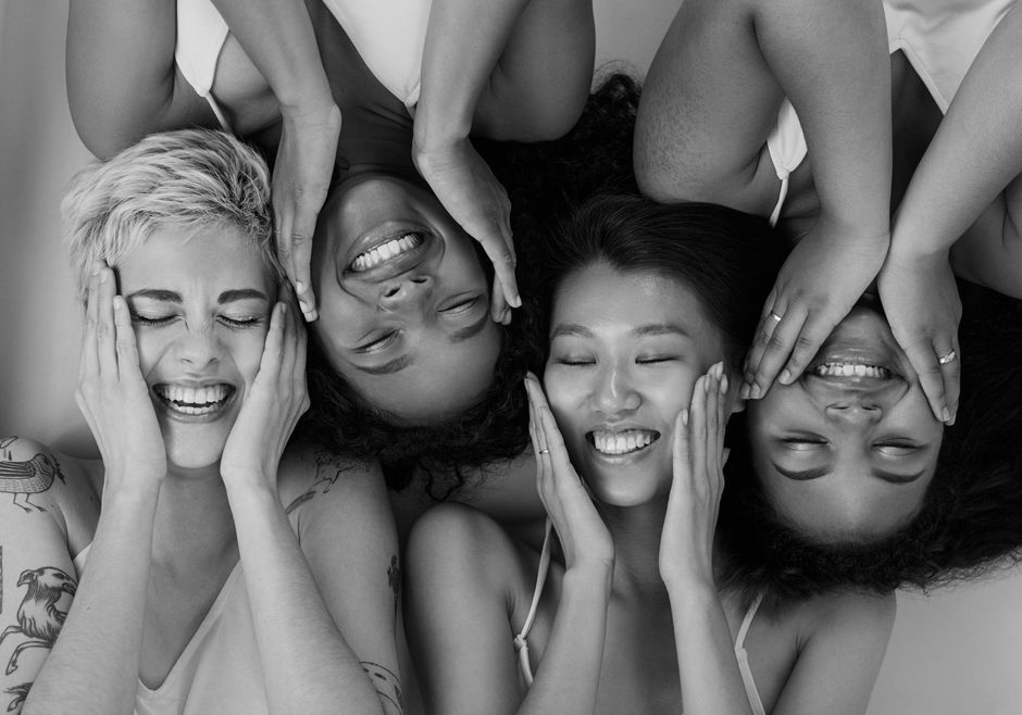 A group of women are laughing together in a black and white photo.