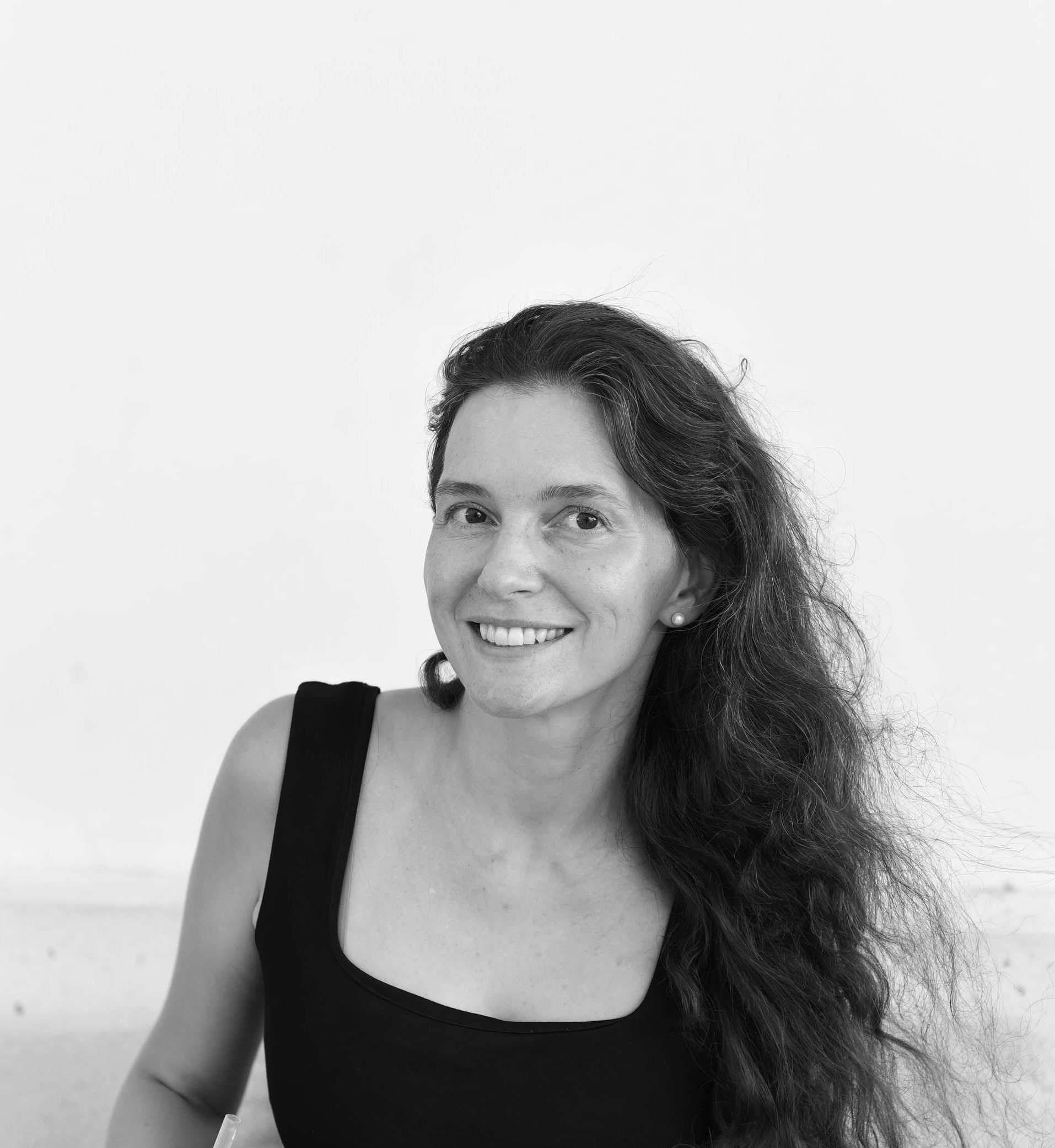 A woman with long hair is smiling in a black and white photo.