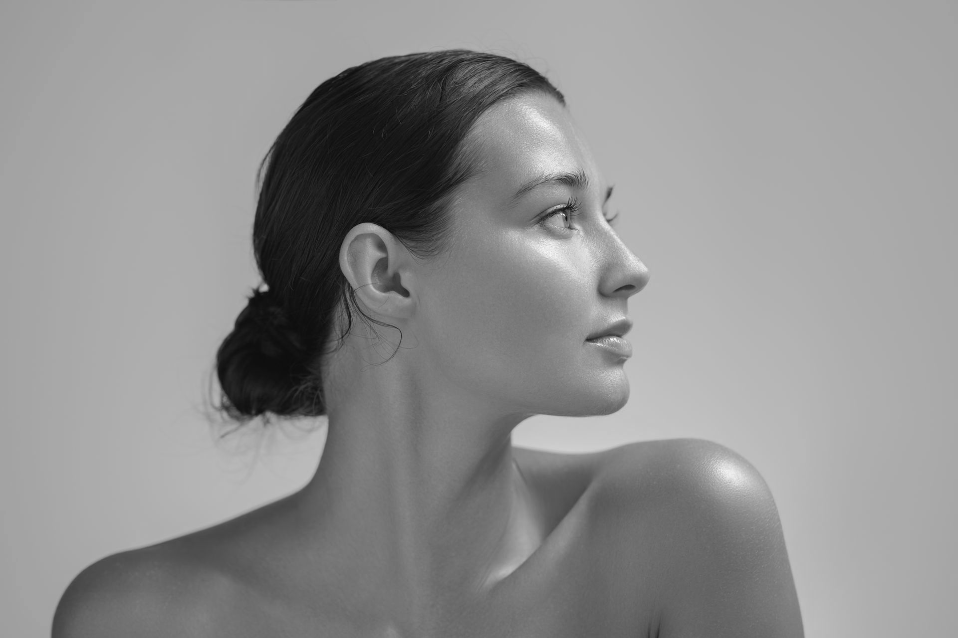 A black and white photo of a woman with her hair in a bun.