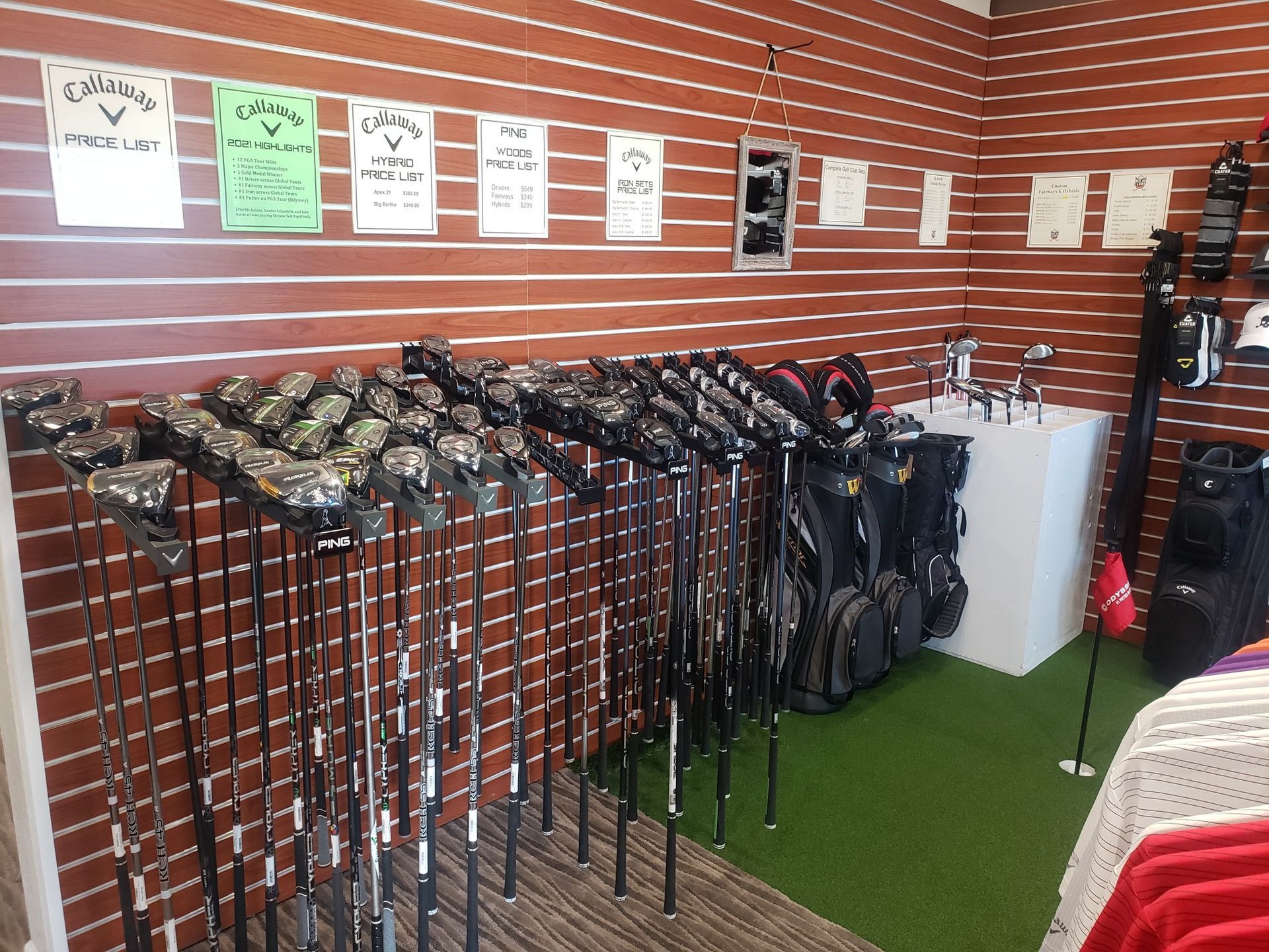 A bunch of golf clubs are hanging on a rack in a store.
