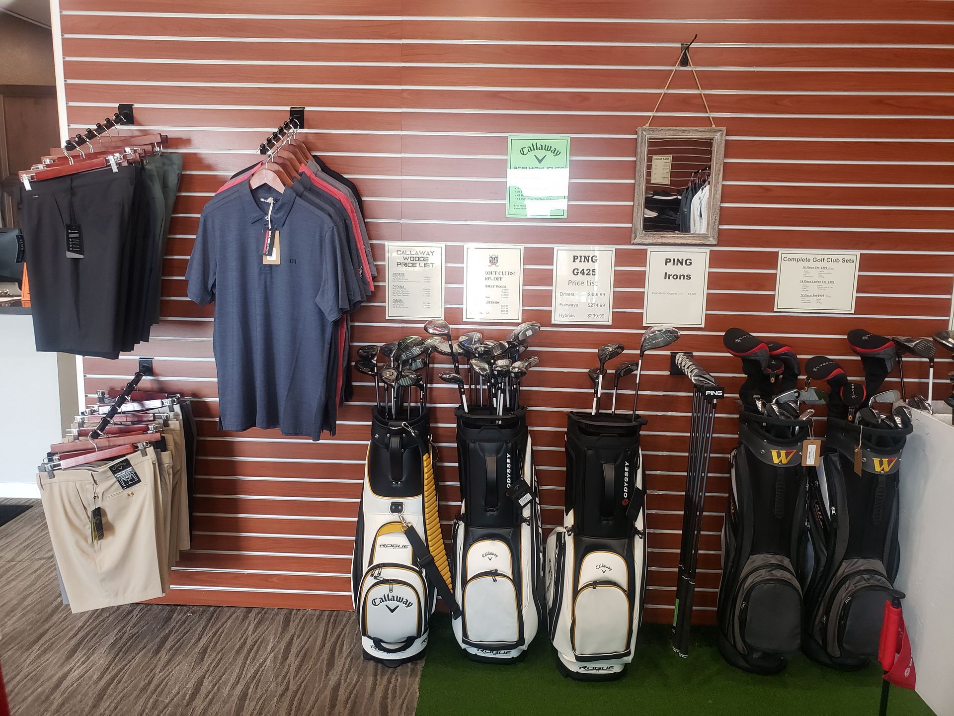 A row of golf bags are lined up in front of a wooden wall.
