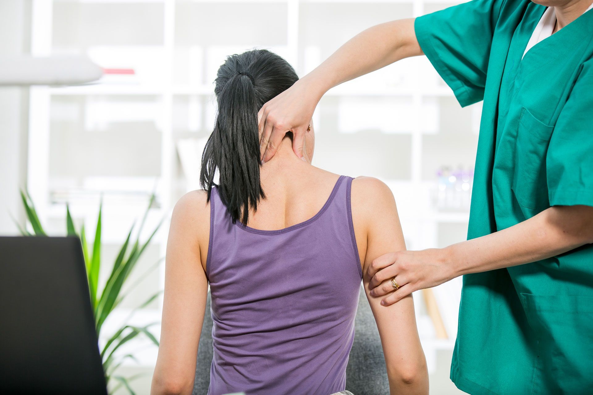 A woman is getting a massage from a doctor while sitting in a chair.