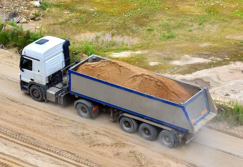 White and Silver Dump Truck Carrying a Load of Sand on a Dirt Road — Tyzac Group in Gympie, QLD