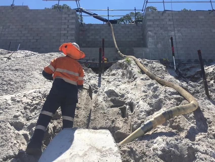Construction Worker Operating a Hose on a Sandy Construction Site — Tyzac Group in Beerwah, QLD