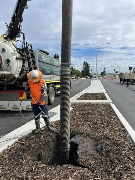 Worker in Orange Vest Sprays Base of a Utility Pole Next to a Truck on a Newly Paved Road — Tyzac Group in Beerwah, QLD